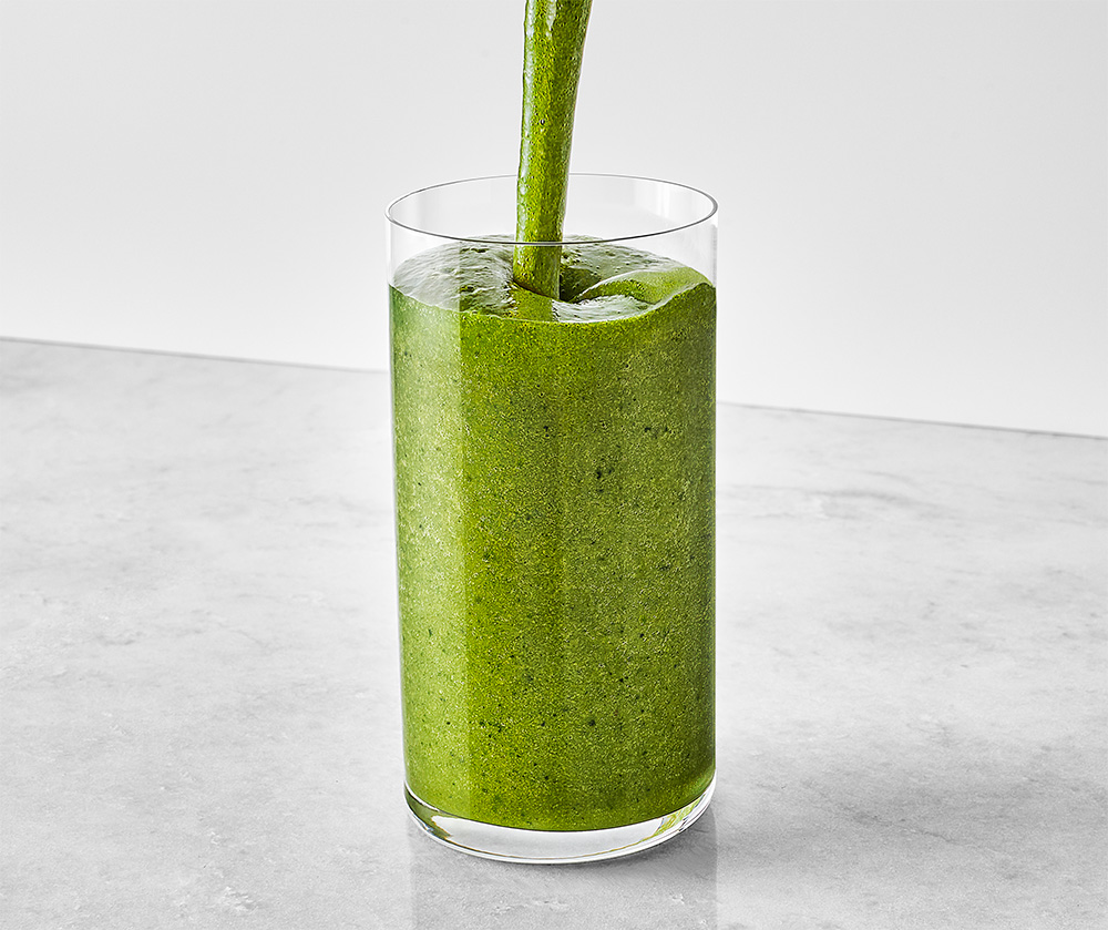 green smoothie being poured into a glass