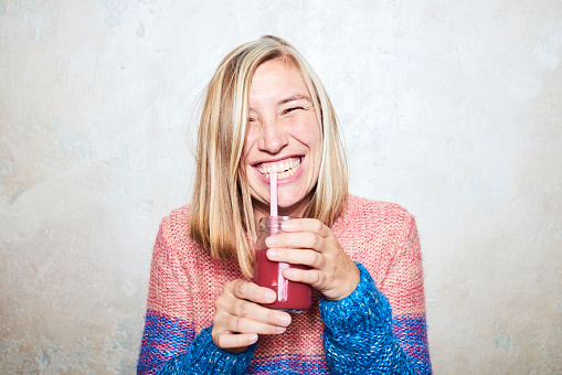 woman smiling while drinking smoothie