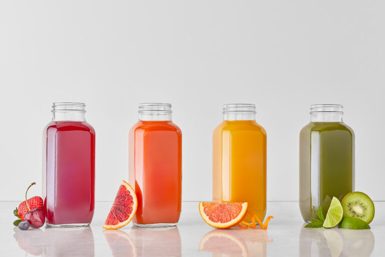pressed juice in bottles with fruit next to them