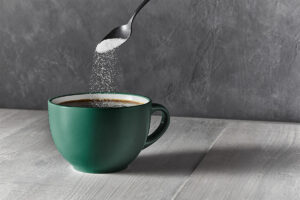 sugar pouring from a spoon into coffee